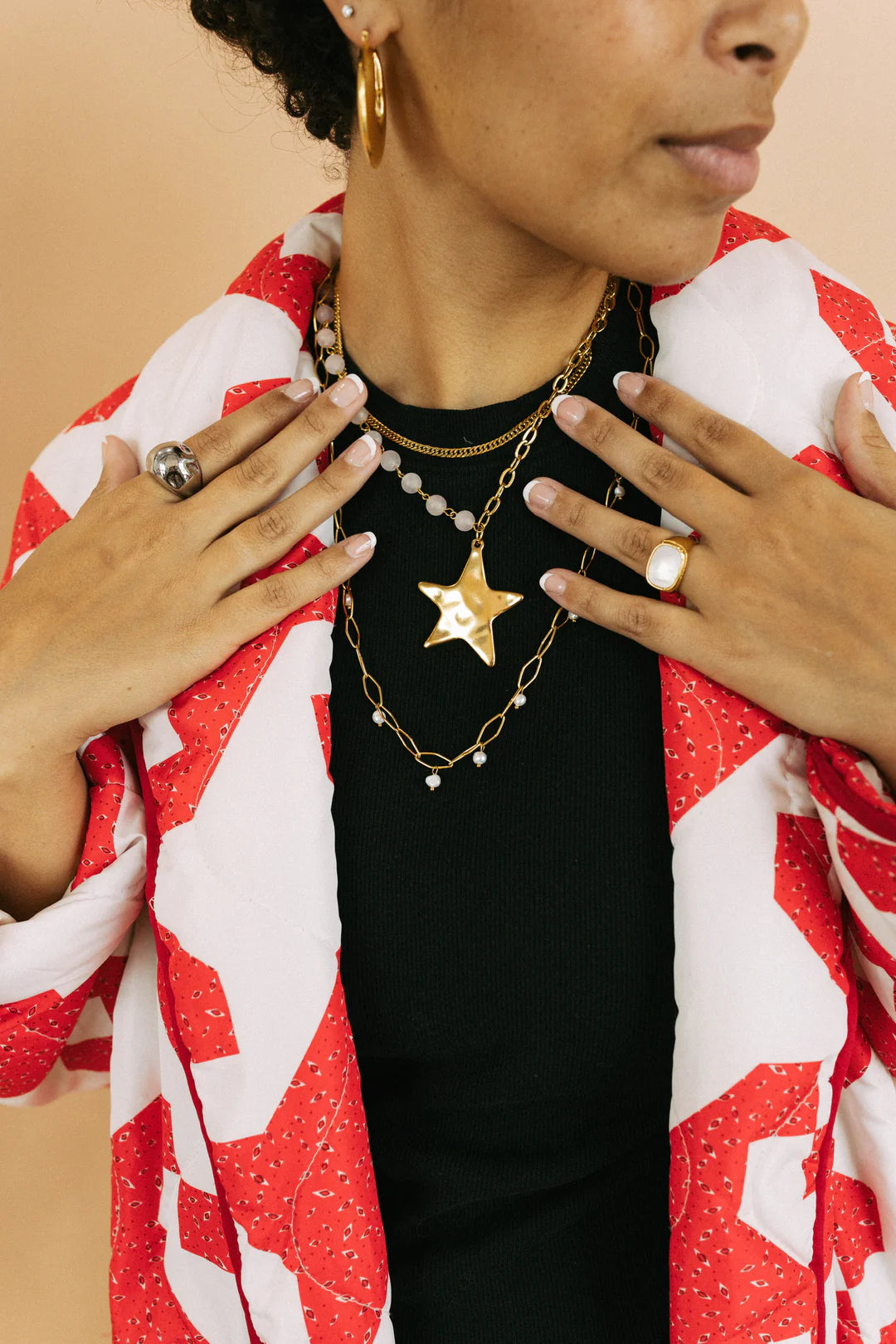 Gold beaded chain necklace with pearl accents layered on black top