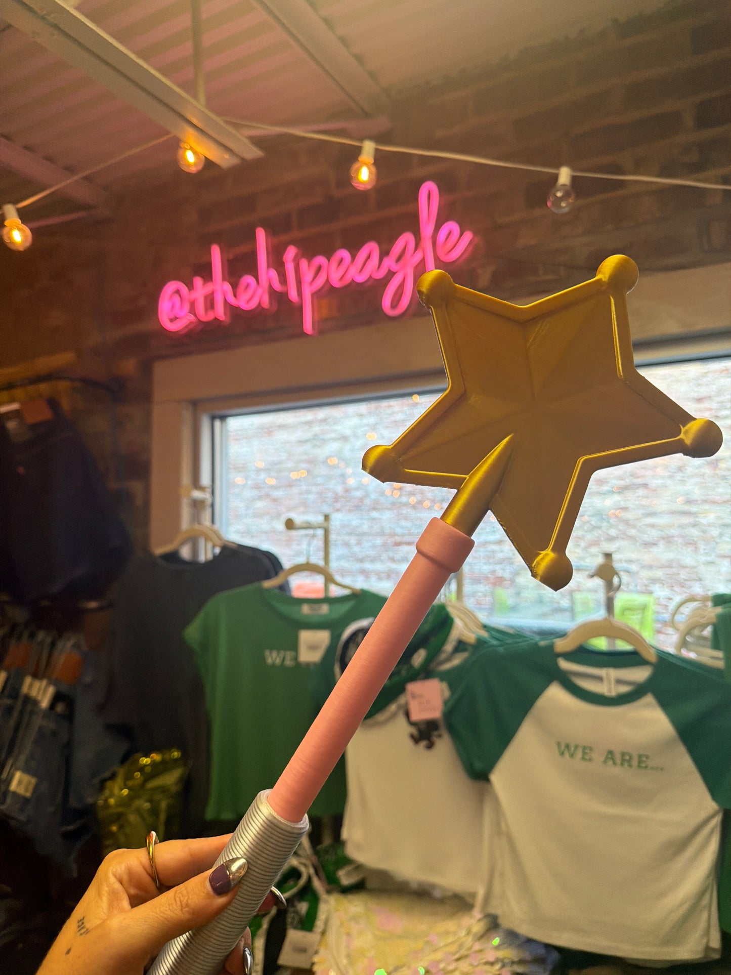 Gold star magic wand with pink handle held up in boutique store