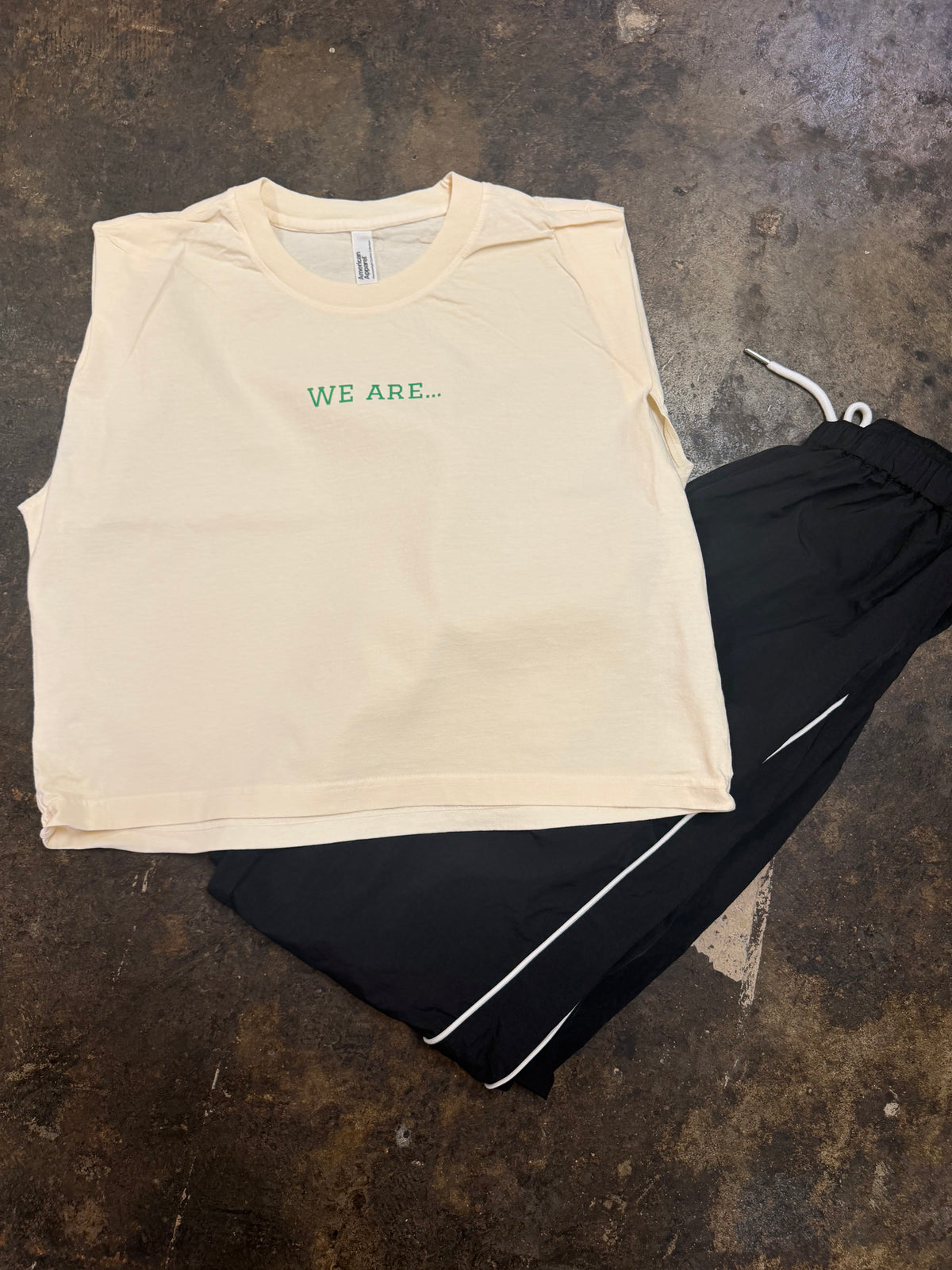 Off-white sleeveless muscle tee with green WE ARE... text on chest