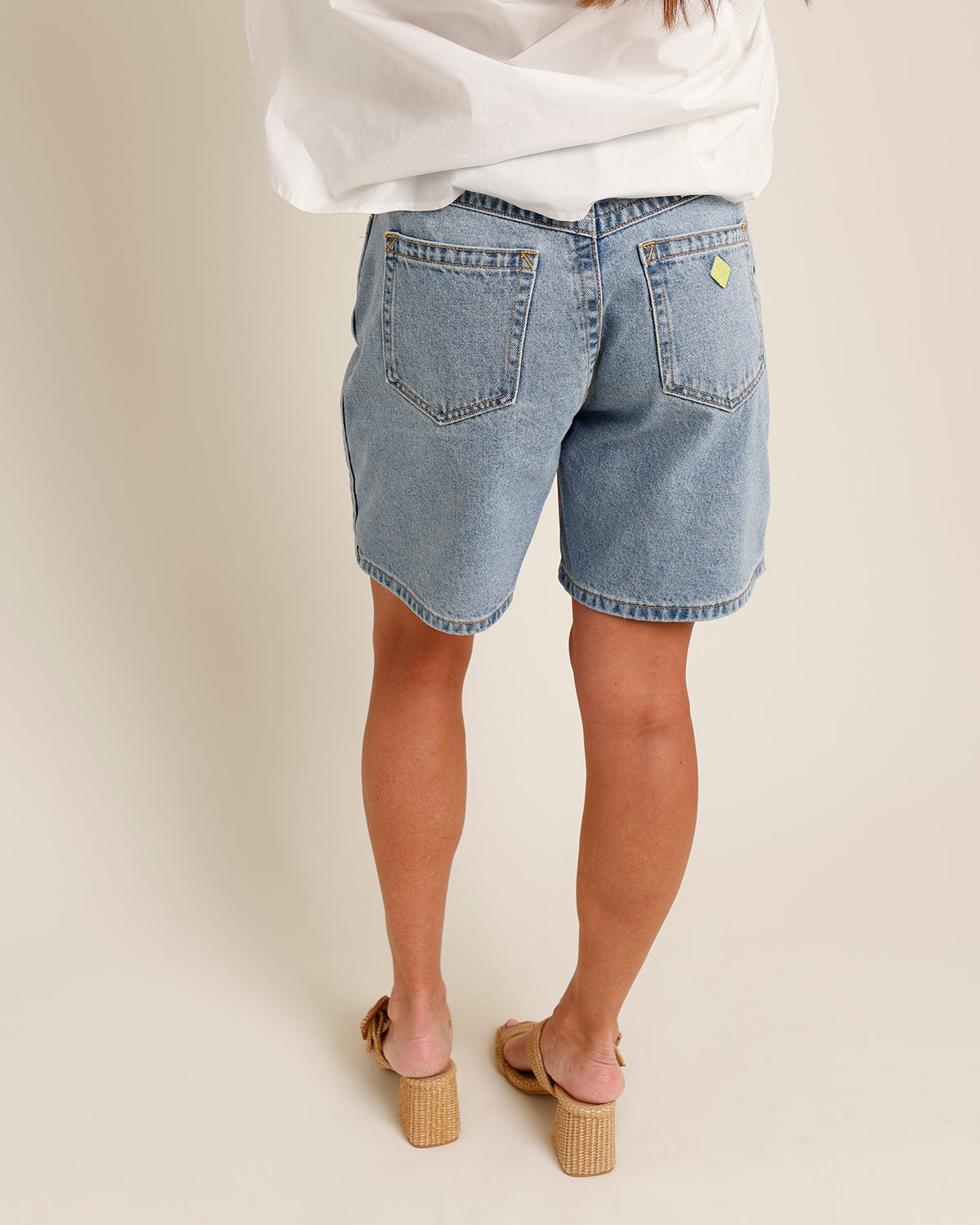 mid-weight indigo denim high waisted relaxed fit wide leg light blue stonewash faded gold stitching mid length denim shorts