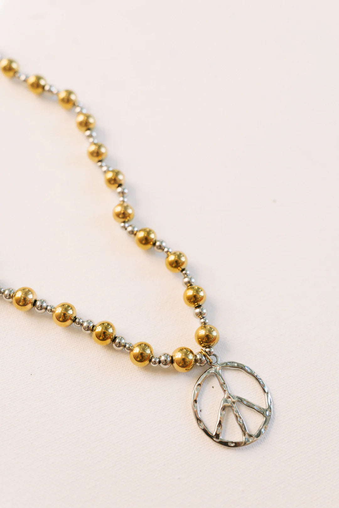Mixed metal beaded necklace with gold and silver beads and silver peace sign pendant