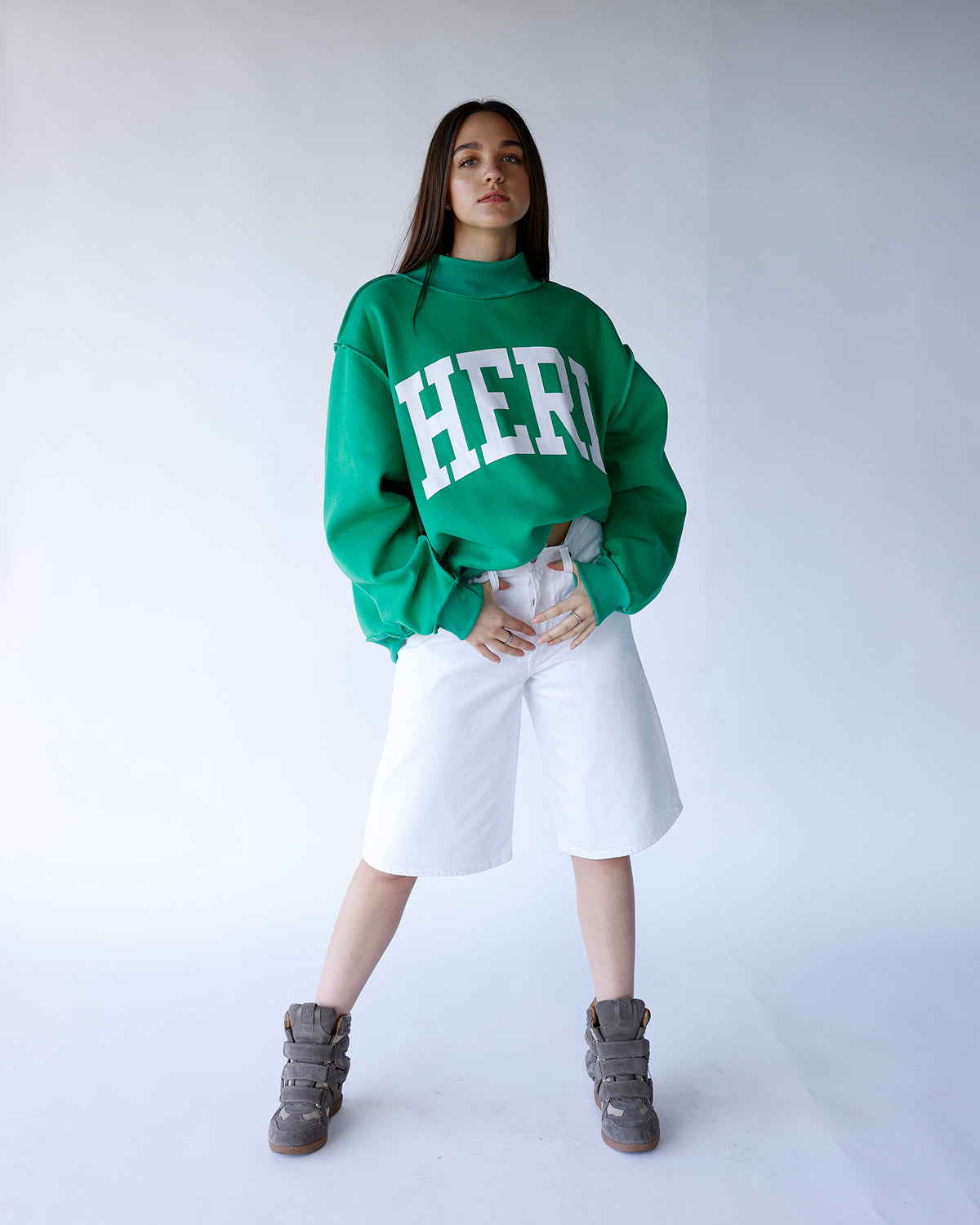 White wide-leg denim bermuda shorts, knee-length, high-rise, worn with green sweatshirt