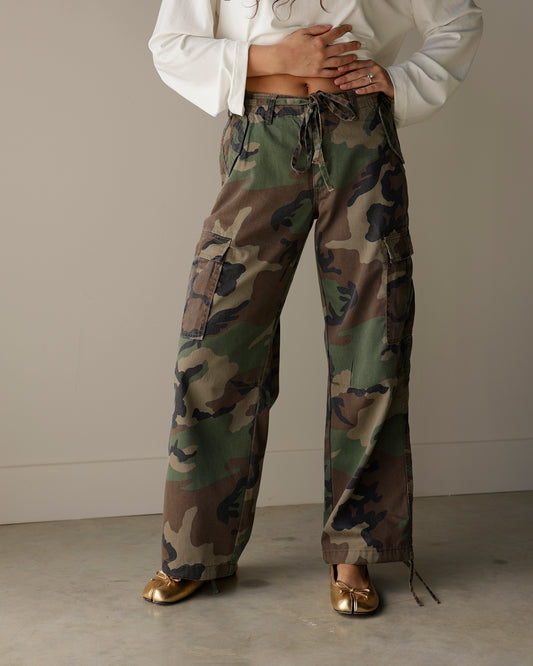 woman wearing veveret woodland camouflage wide-leg cargo pants with oversized flap pockets, tie waistband and metallic gold ballet flats.