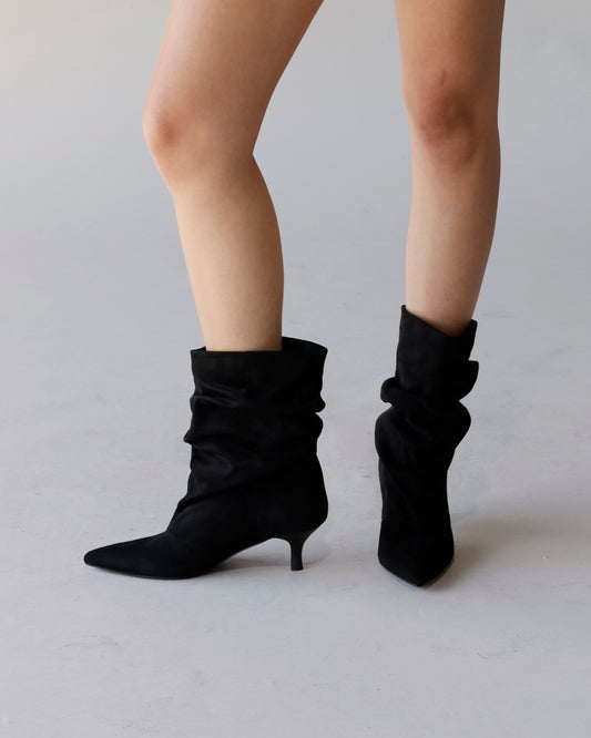 Black suede slouch ankle booties with kitten heel and pointed toe on model