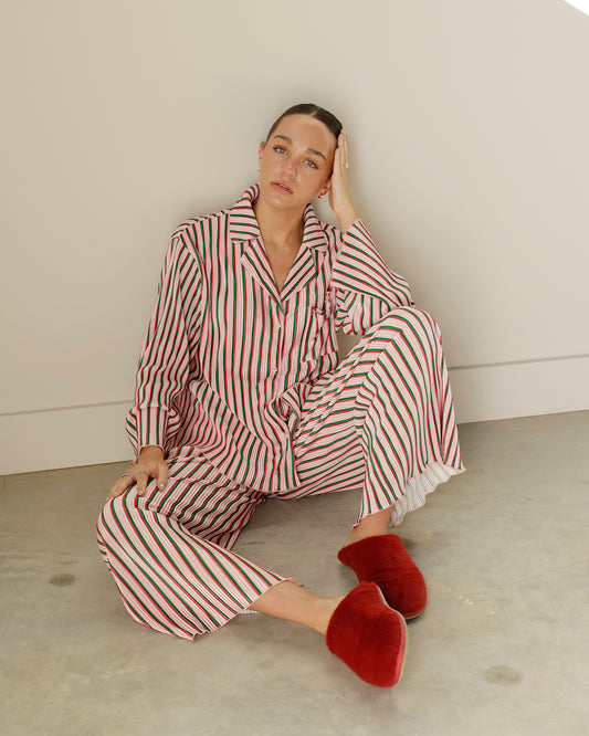 peach love two-piece christmas pajama set featuring pink, red, green and white vertical stripes, a button-down collared top and matching wide-leg pants.