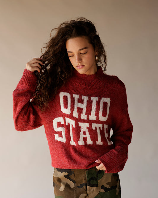 Red knit Ohio State mock-neck sweater with white varsity letters, worn with camo pants