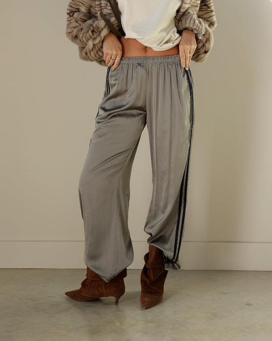 Loucia taupe-gray satin-look track pants featuring contrasting black double side stripes, an elastic waistband, side pockets and a relaxed wide-leg silhouette.