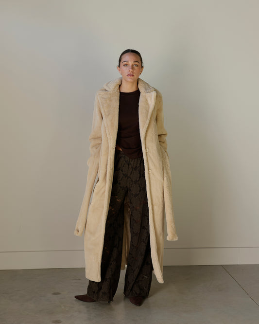 loucia ivory faux fur maxi coat with oversized notched lapels, a matching tie waist belt, front button closure and long sleeves with button-tab cuffs.