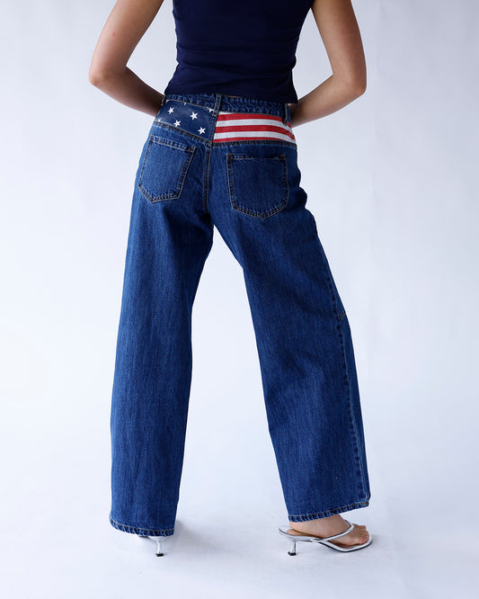 Dark denim wide leg jeans featuring an American flag detail above the back pockets. A bold, patriotic statement piece with a relaxed, trendy fit.
