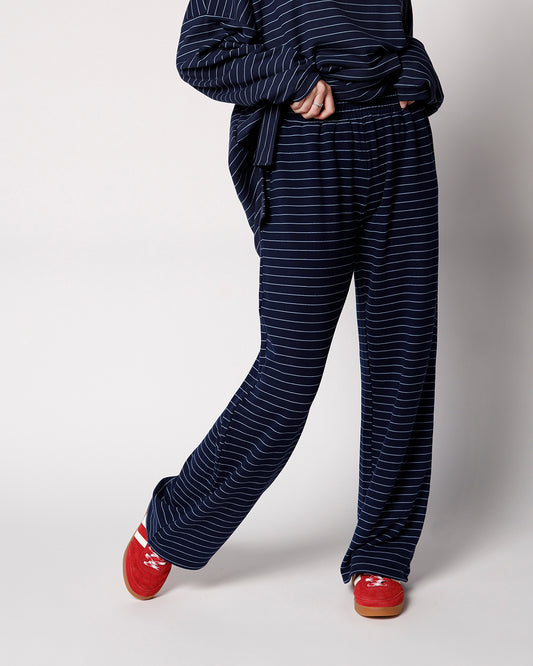 Navy blue striped wide-leg lounge pants with elastic waist, styled with red sneakers