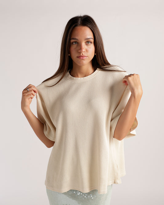 Elevate your everyday wardrobe with this cream waffle-knit top featuring a relaxed boxy fit, drop shoulders, elbow-length sleeves, and a cozy textured finish. Perfect for pairing with denim or dressing up with skirts for effortless, everyday style.