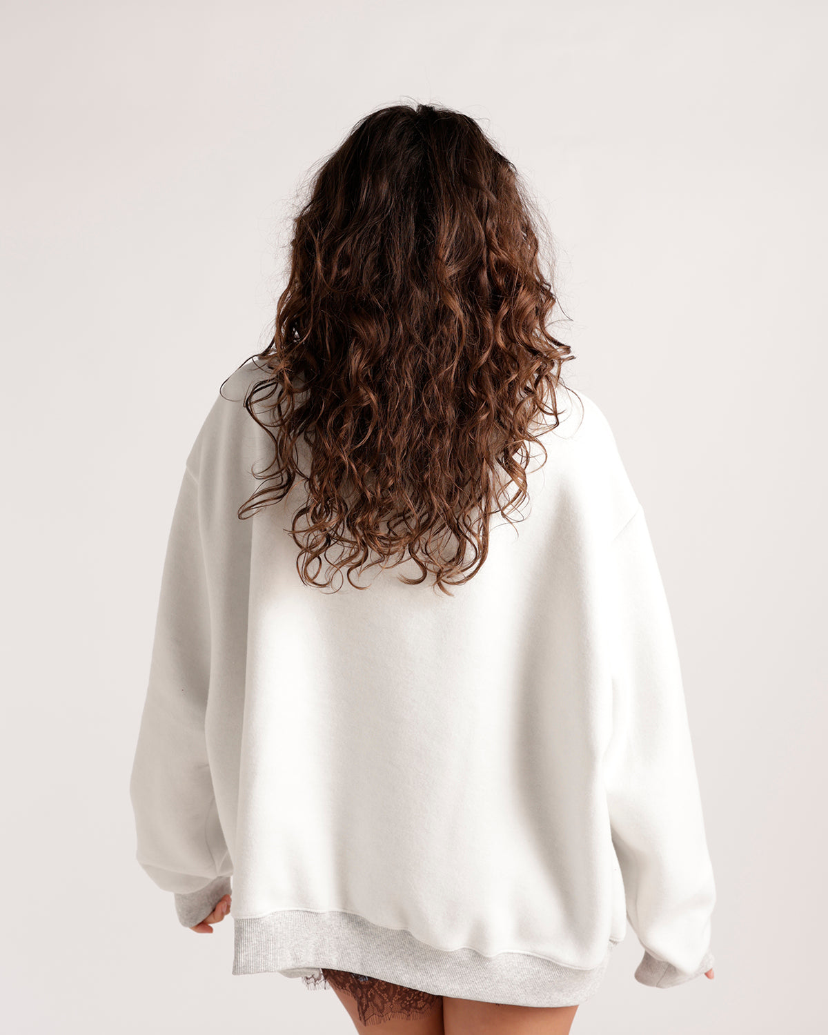 Back view of oversized white crewneck sweatshirt with gray ribbed hem