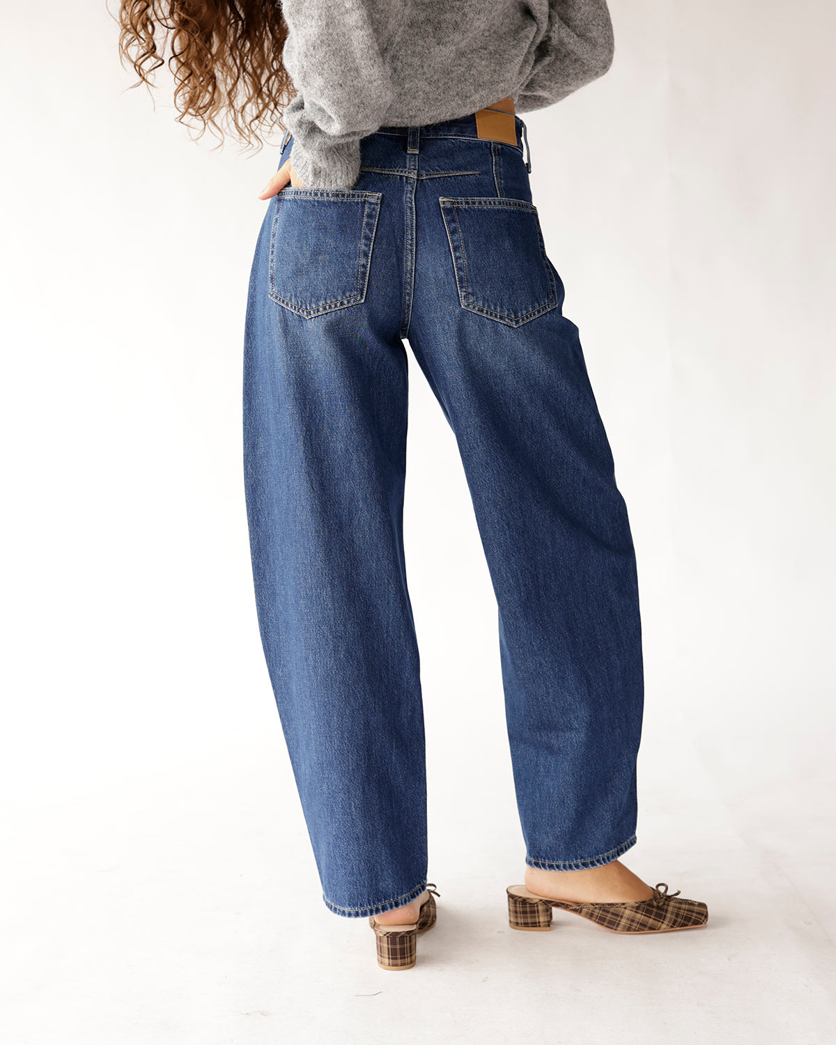 Dark blue high rise relaxed barrel jeans, back view, worn with plaid mules