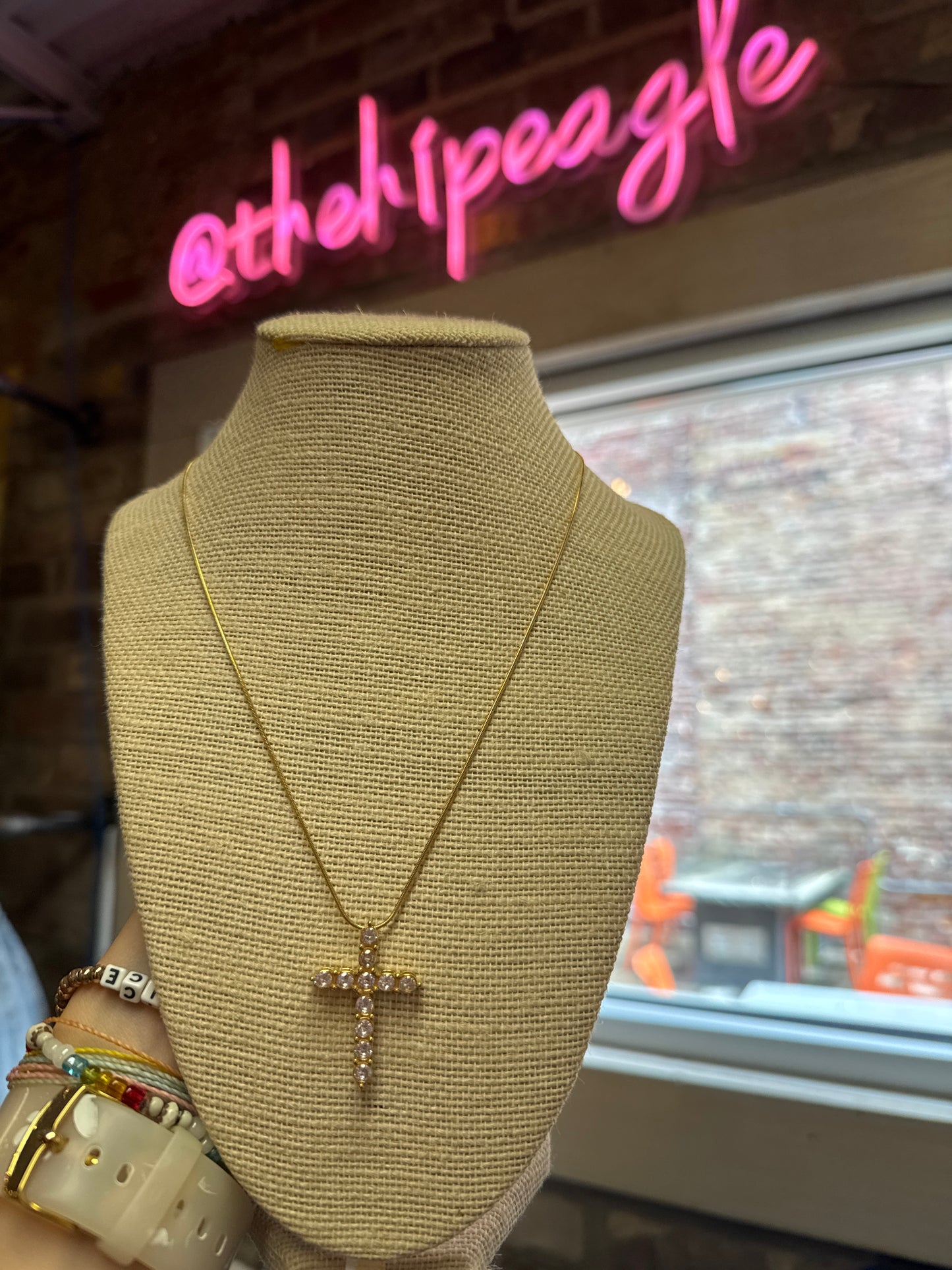 Gold chain necklace with crystal rhinestone cross pendant on burlap display bust