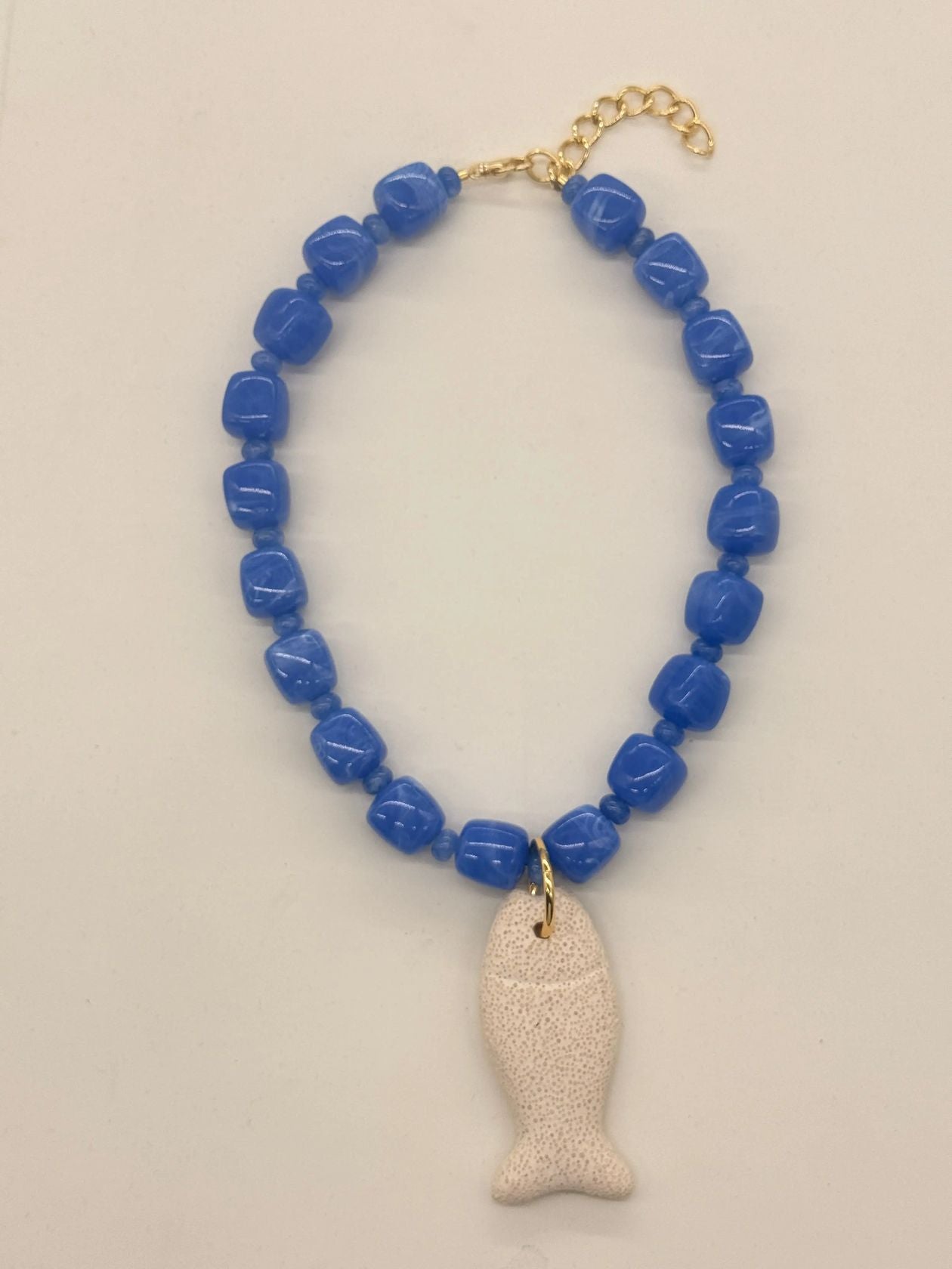 this necklace is a bold, coastal inspired statement piece with an earthy, textured feel. designed with chunky resin beads and gold accent beads. a lava stone fish pendent adds a unique ocean-inspired detail, giving the piece a playful yet elevated beachy edge.