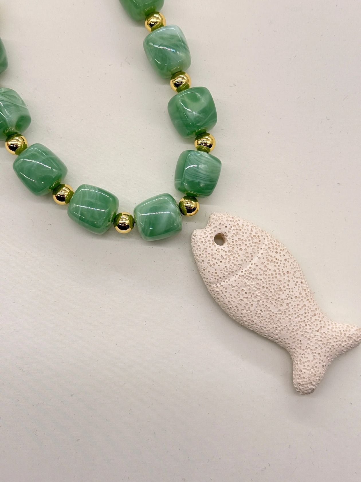 Beaded necklace with jade green and gold beads, white lava stone fish pendant