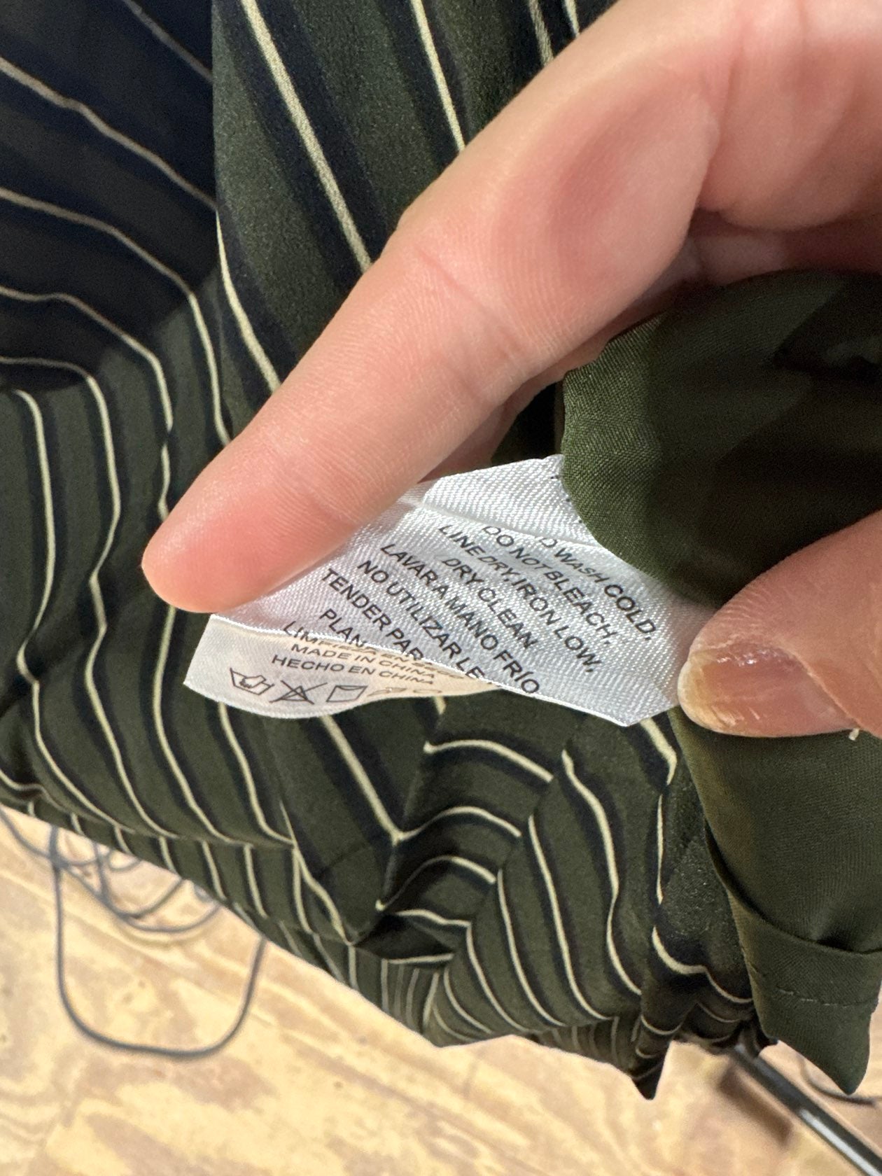 Dark olive green striped blouse care label showing cold wash dry clean instructions
