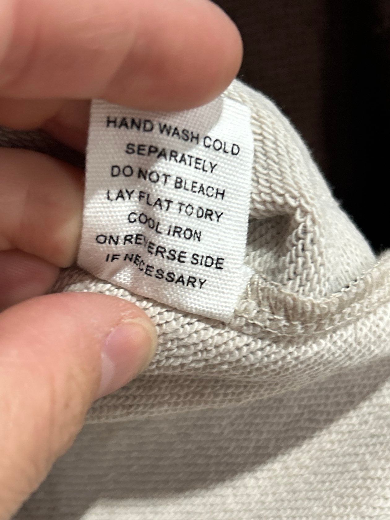 White clothing care label showing hand wash cold, do not bleach, lay flat to dry instructions