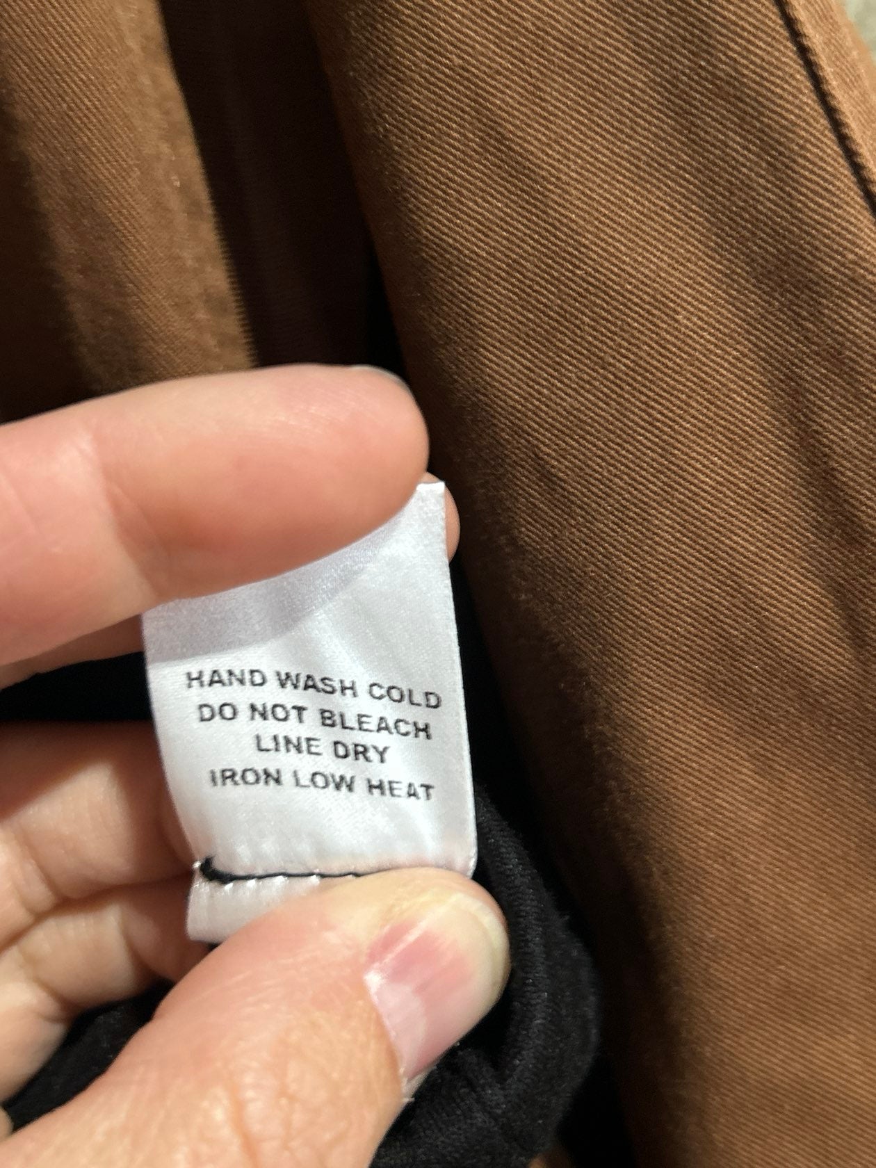 Care label on brown dressy pants: hand wash cold, do not bleach, line dry, iron low heat.