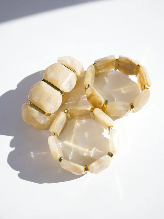 Three cream and gold stretch bracelets with flat stone beads arranged together