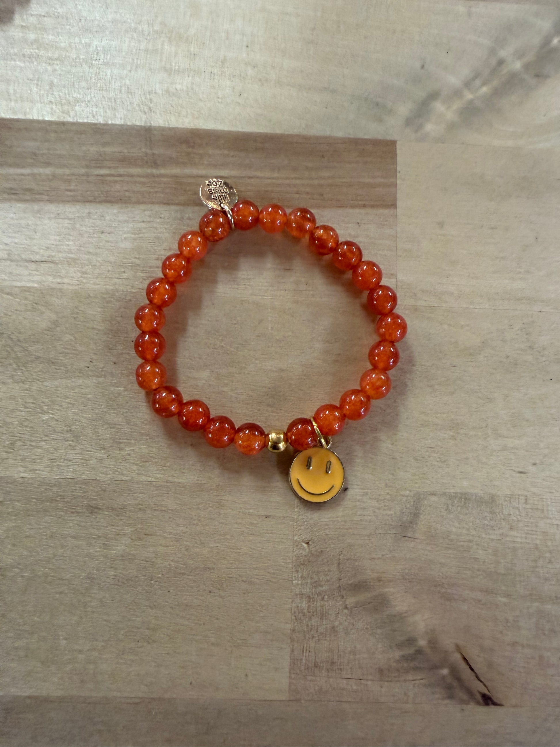 Orange beaded stretch bracelet with a gold smiley face charm pendant