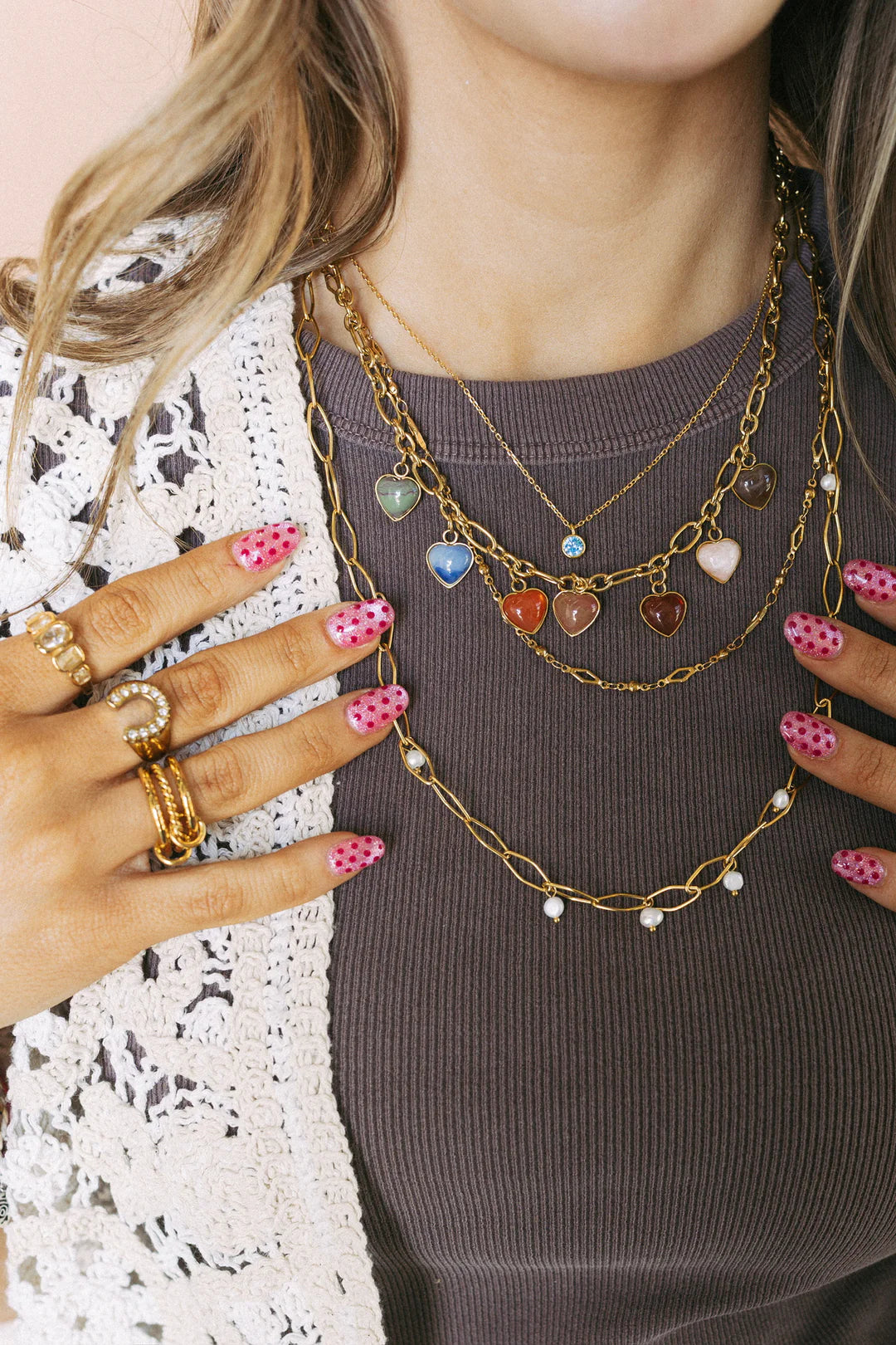 Layered gold chain necklace with colorful heart-shaped stone charms in multiple colors
