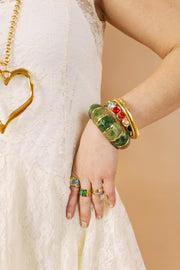 Green stretch bracelet with red gemstone accents worn on wrist