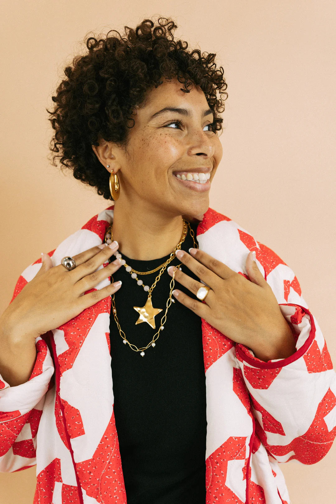 Gold star pendant layered chain necklace with pearl accents worn by smiling woman