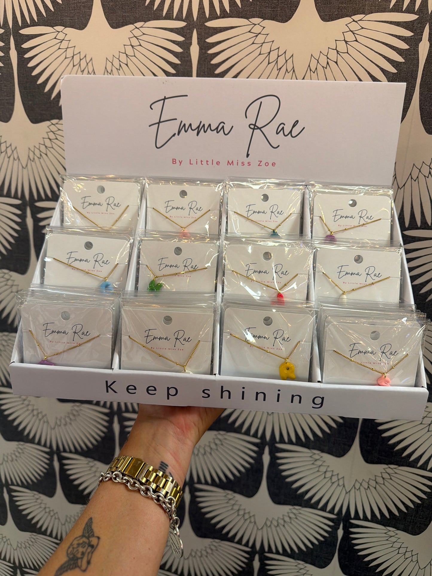 Gold chain necklaces with colorful bubble initials displayed in retail box tray