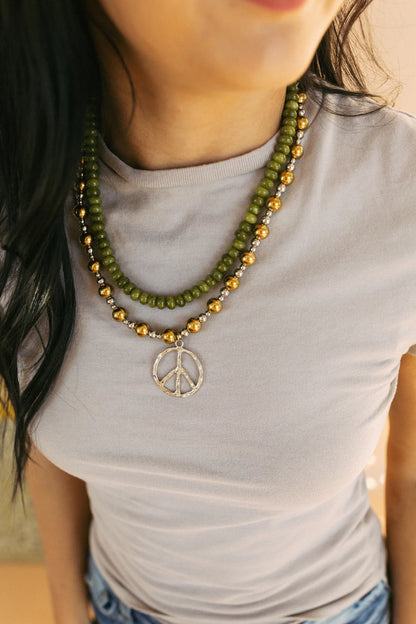 Layered green beaded and mixed metal necklace with silver peace sign pendant