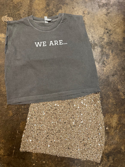 Vintage washed black muscle tee with WE ARE... graphic, paired with gold sequin skirt