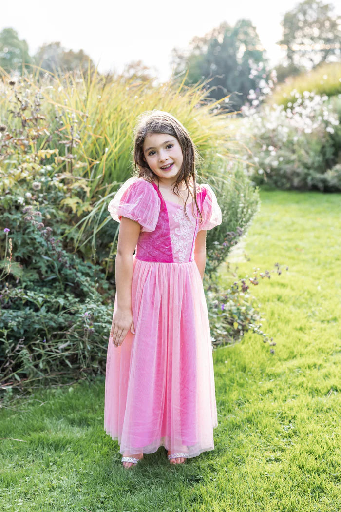 Girl wearing long pink tulle princess dress with puff sleeves in garden