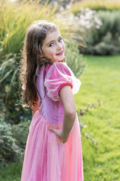 Girl wearing pink and purple princess dress with sheer puff sleeves in garden
