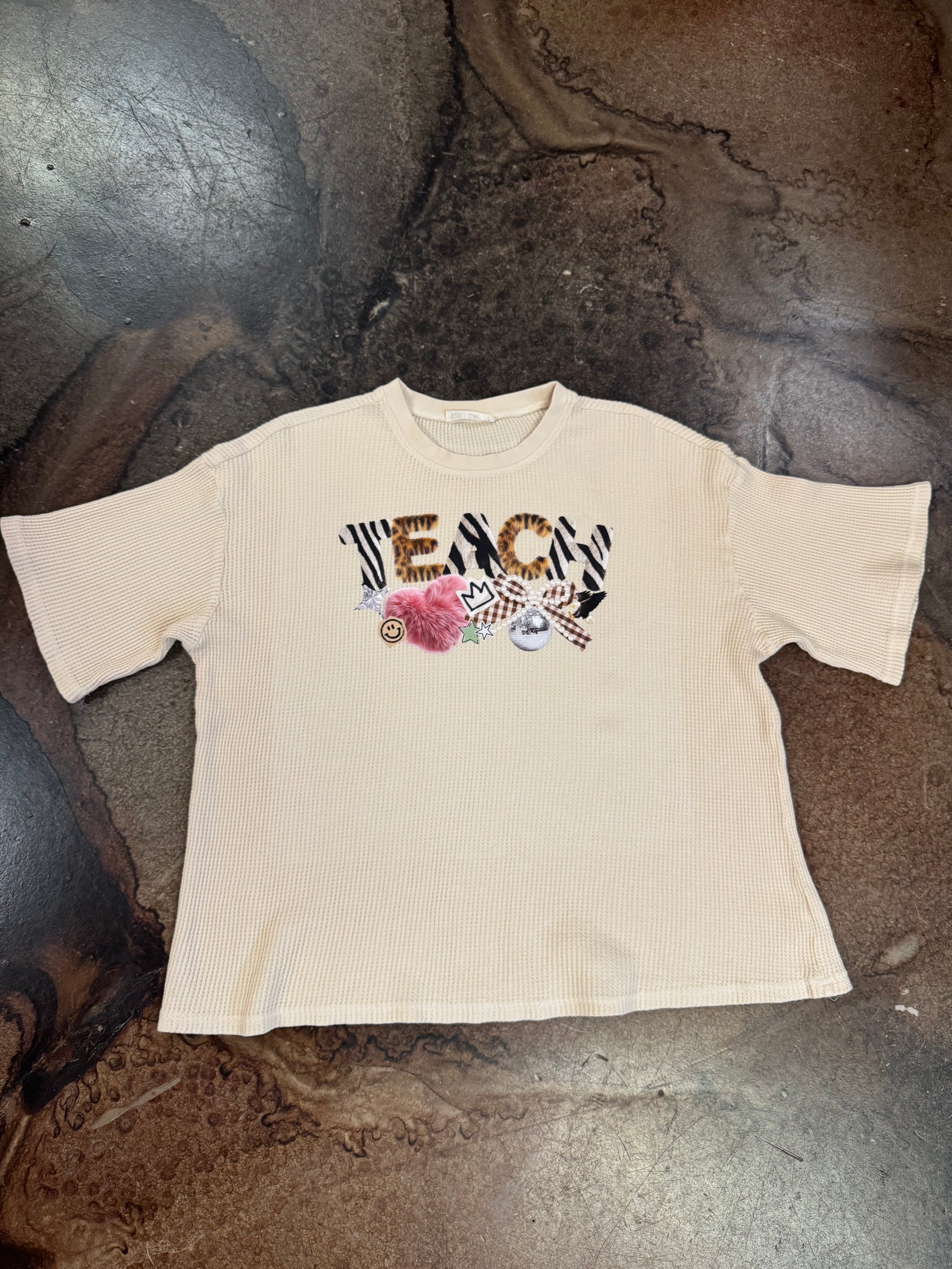 Cream waffle knit tee with animal print TEACH graphic and fun charms