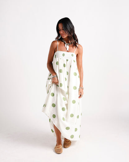 White maxi dress with green polka dots, smocked bodice, and thin straps