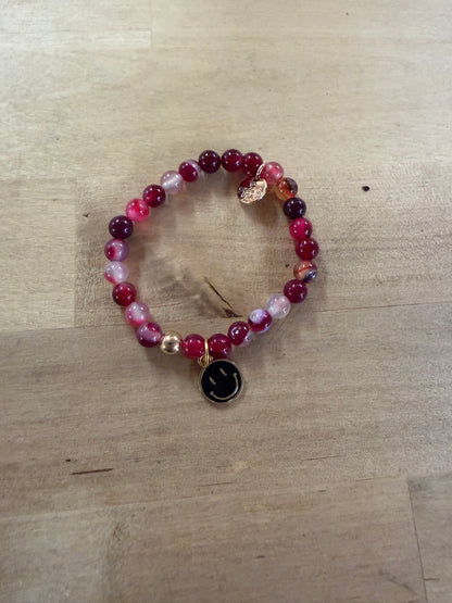 Pink agate beaded stretch bracelet with black enamel smiley face gold charm