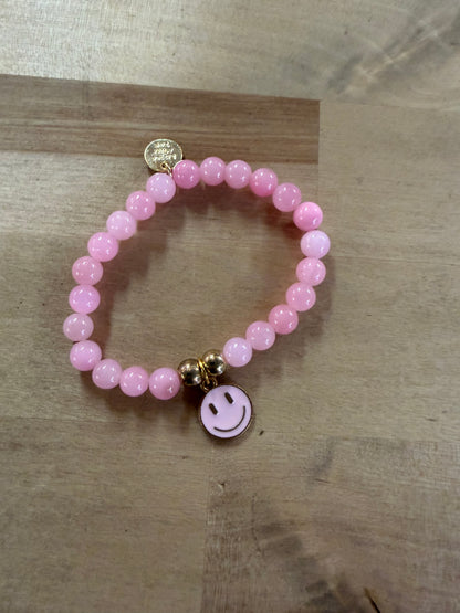 Pink beaded stretch bracelet with gold smiley face enamel charm