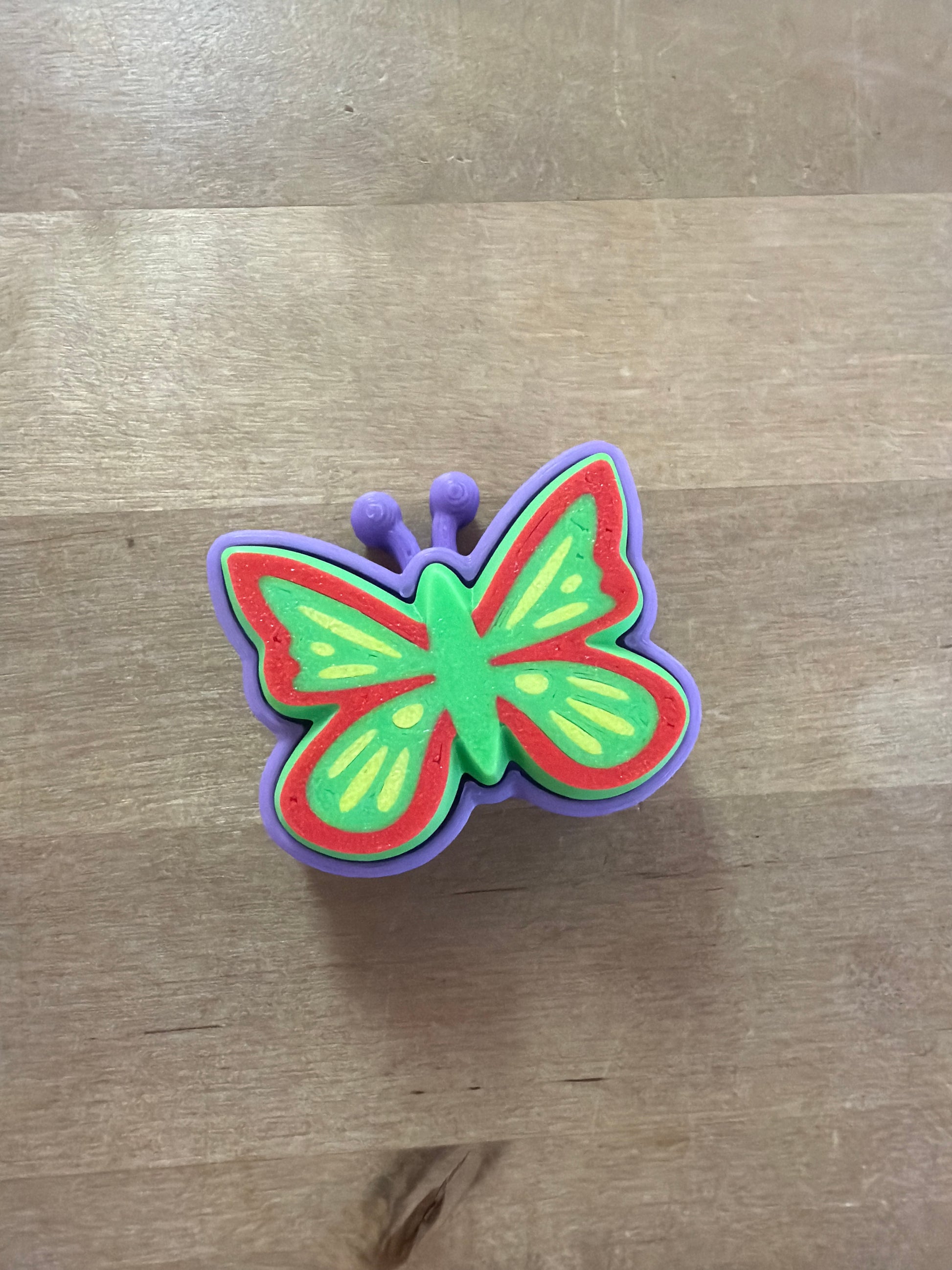 Colorful butterfly XL clicker toy in green, red, and purple with yellow wing details