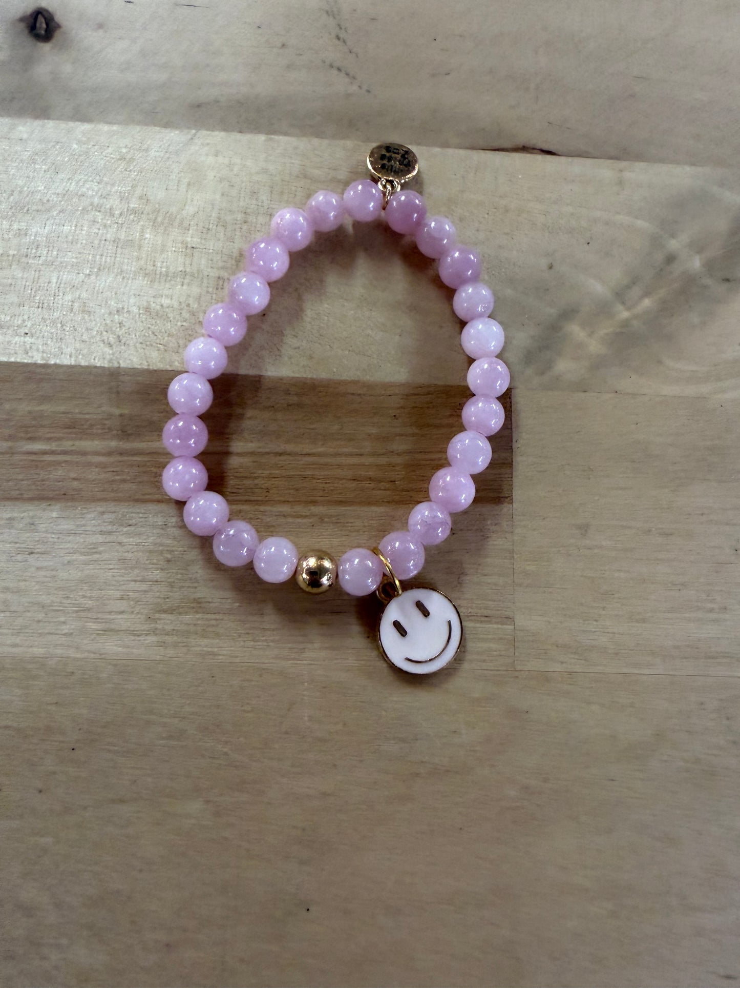 Pink beaded stretch bracelet with gold accent bead and white enamel smiley face charm