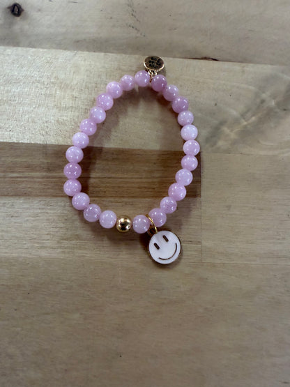Pink beaded stretch bracelet with gold accent bead and white enamel smiley face charm