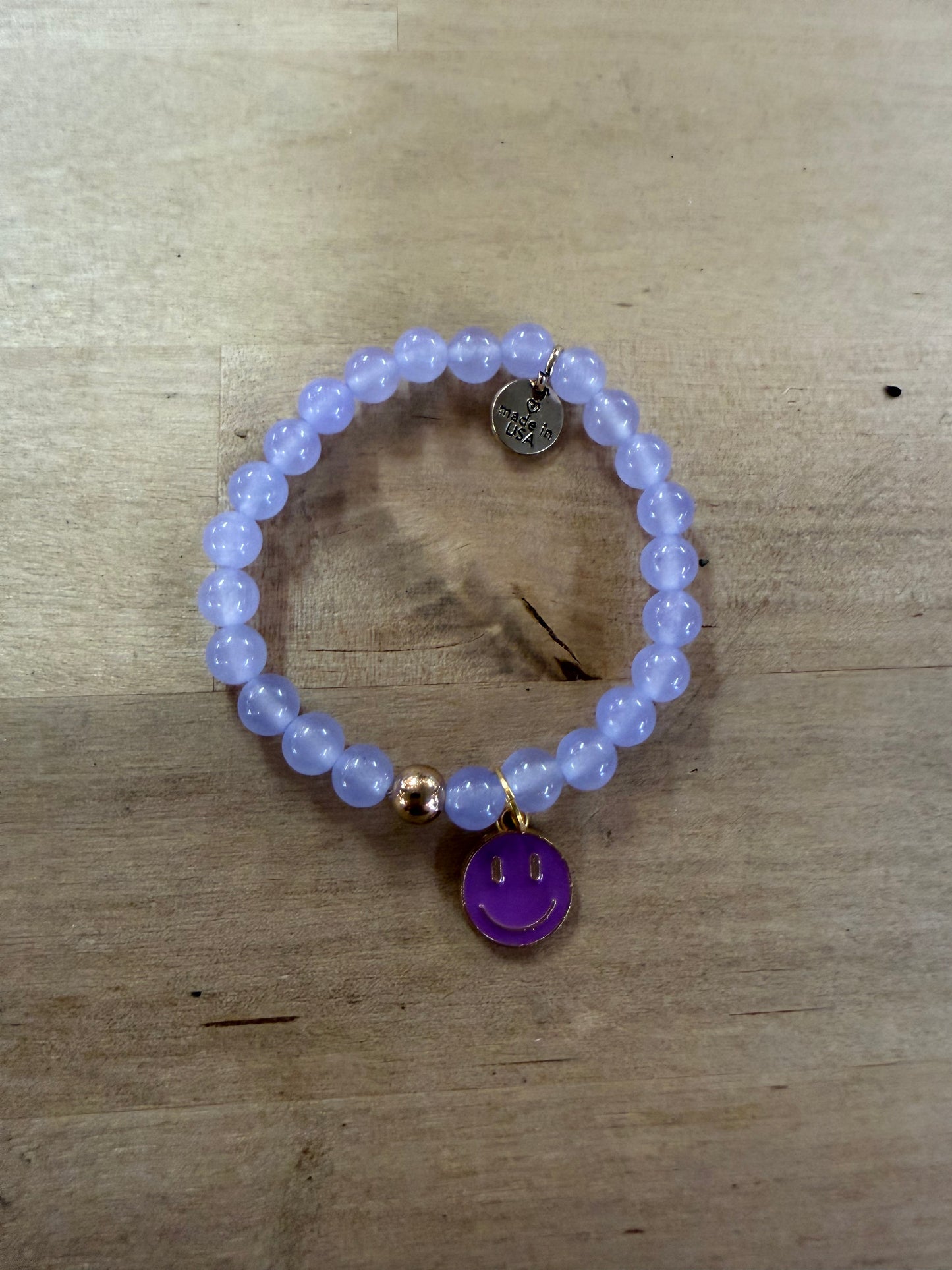 Lavender beaded stretch bracelet with purple enamel smiley face gold-rimmed charm