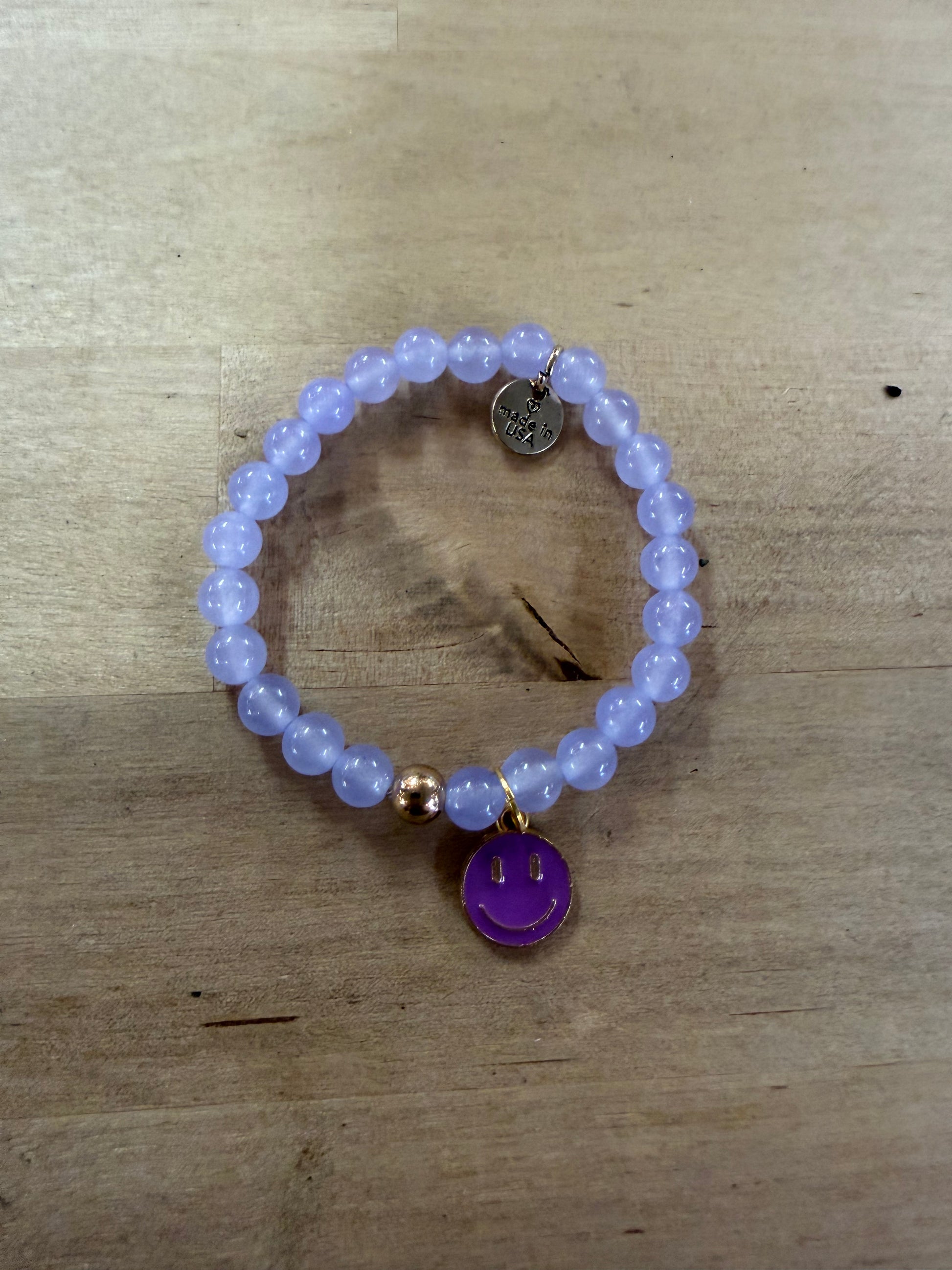 Lavender beaded stretch bracelet with purple enamel smiley face gold-rimmed charm