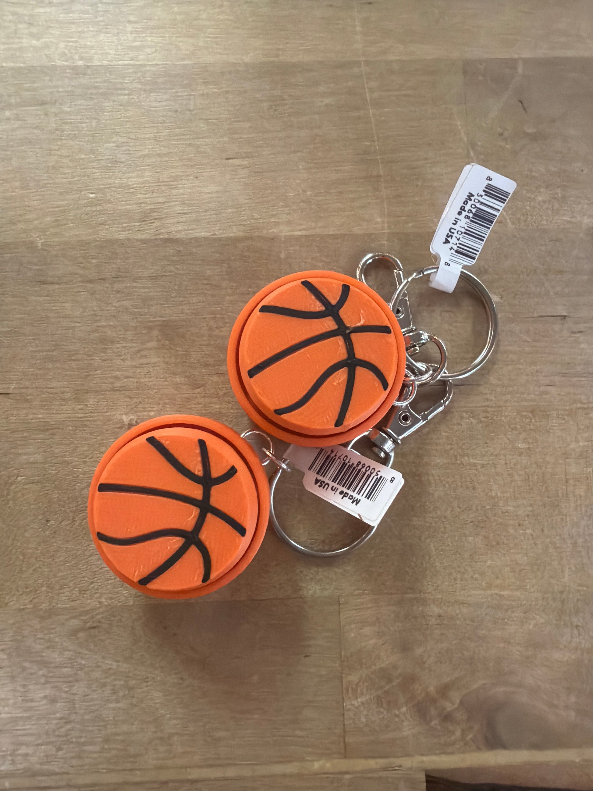 Two orange basketball-shaped clicker keychains with black seam lines, Made in USA