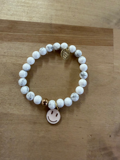 White marble beaded stretch bracelet with gold smiley face charm and logo tag