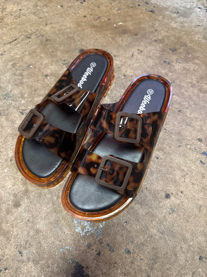 Tortoiseshell jelly slide sandals with double buckle straps and amber platform sole