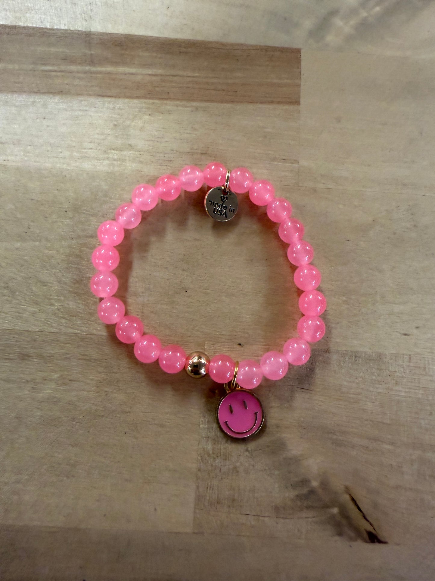 Pink beaded stretch bracelet with gold accents and pink smiley face charm