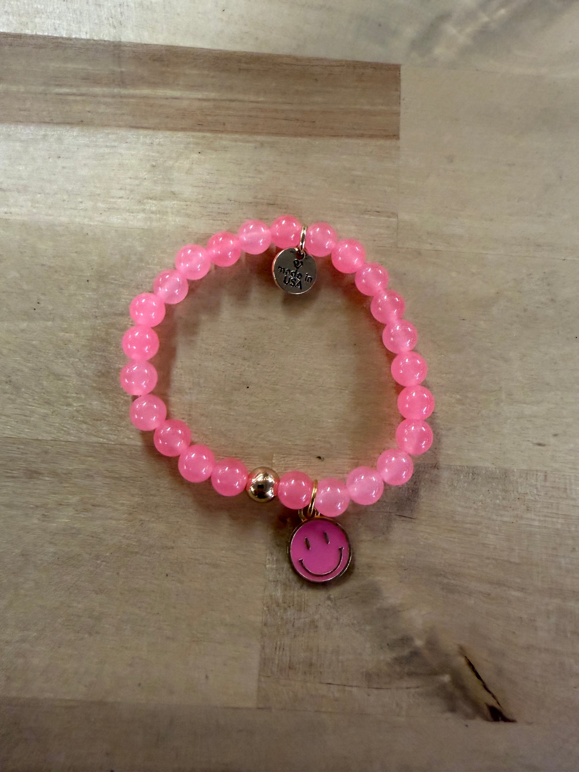 Pink beaded stretch bracelet with gold accents and pink smiley face charm