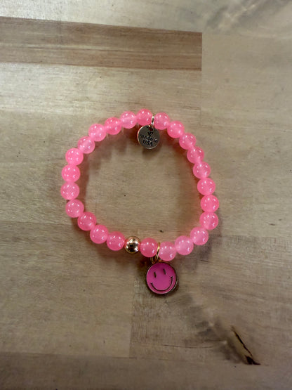 Pink beaded stretch bracelet with gold accents and pink smiley face charm