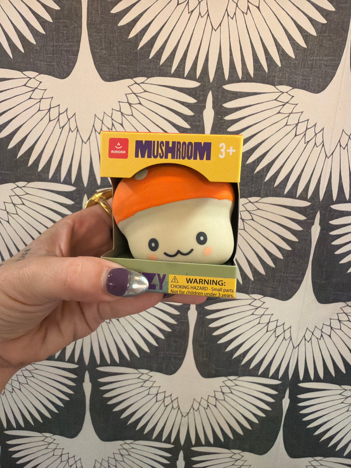 Aurora Mushroom Squeezy toy, white with orange cap, cute face, in yellow box