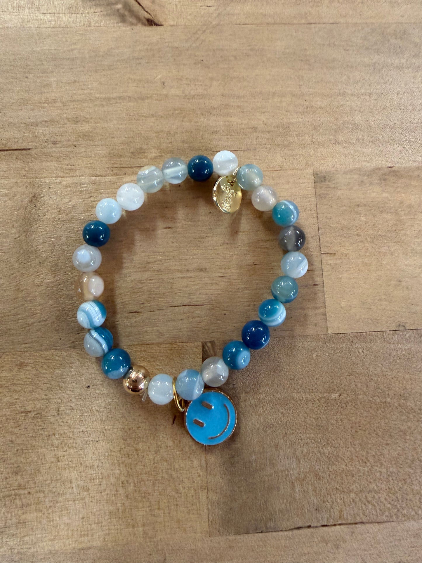 Blue beaded stretch bracelet with smiley face charm and gold accent charm